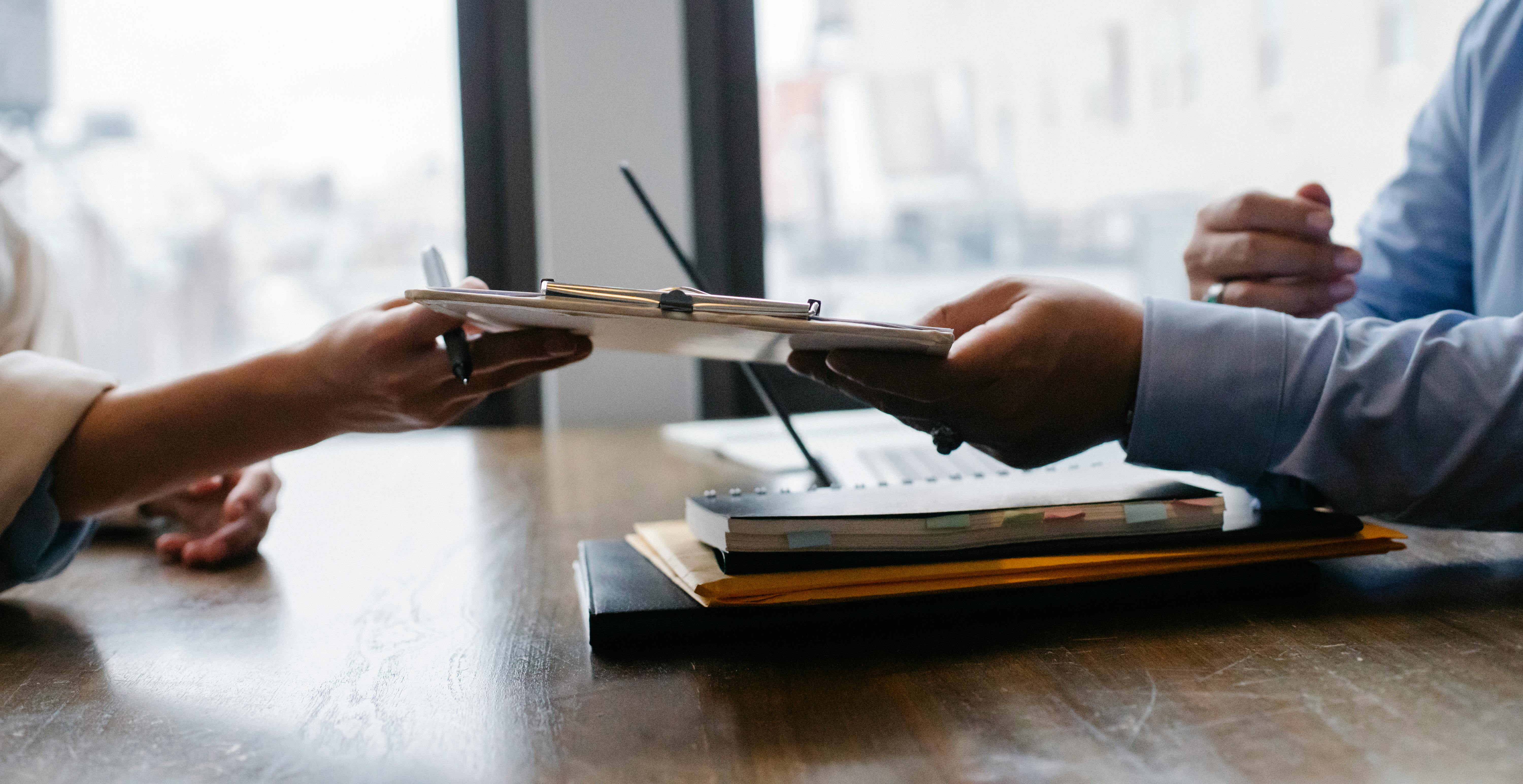 image représenant une femme à gauche tendant un document à un homme situé à gauche, dans un bureau de travail